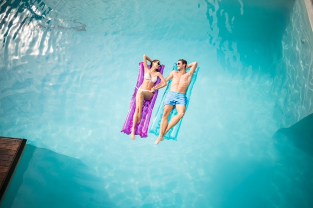 Couple heureux se détendre sur un radeau pneumatique à la piscine