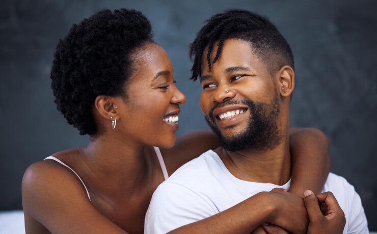 Photo un couple heureux se serre et s'embrasse dans la chambre à coucher pour l'amour, l'amour et la connexion en tant que partenaire dans la relation femme et homme africains pour le soutien avec le sourire intimité et joie dans le mariage pour le lien ou la confiance