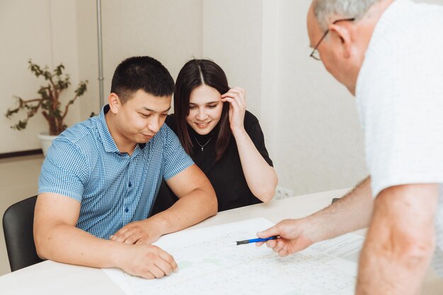 Un couple heureux signe un contrat ensemble au bureau un homme et une femme achètent un appartement et signent un contrat