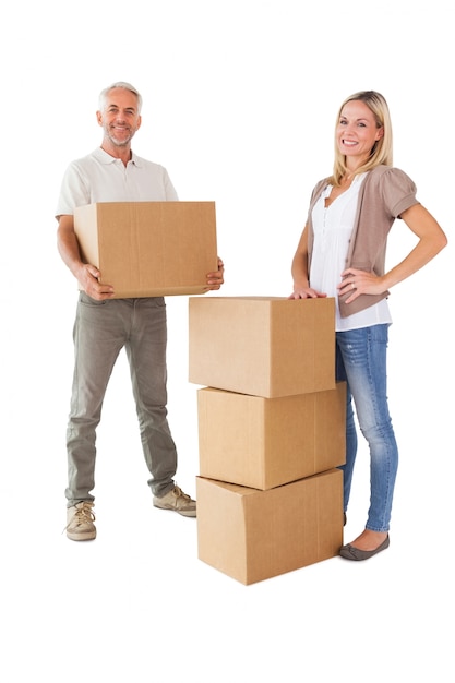 Couple heureux, souriant à la caméra avec des boîtes de déménagement