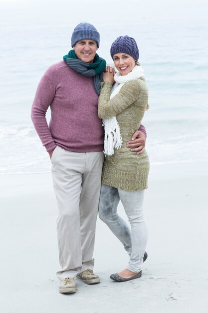 Couple heureux souriant à la fois portant des écharpes et des chapeaux