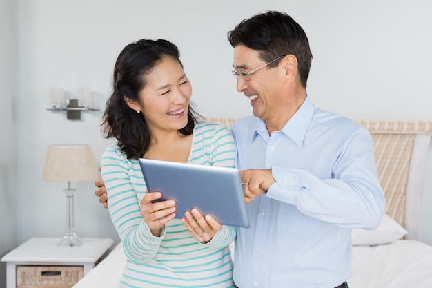 Couple heureux avec tablette dans la chambre