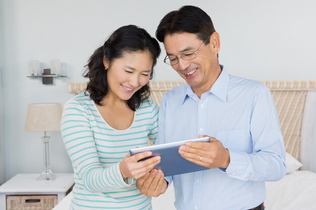 Couple heureux avec tablette dans la chambre