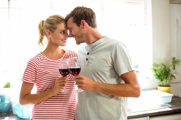 Couple heureux tenant des verres à vin dans la cuisine