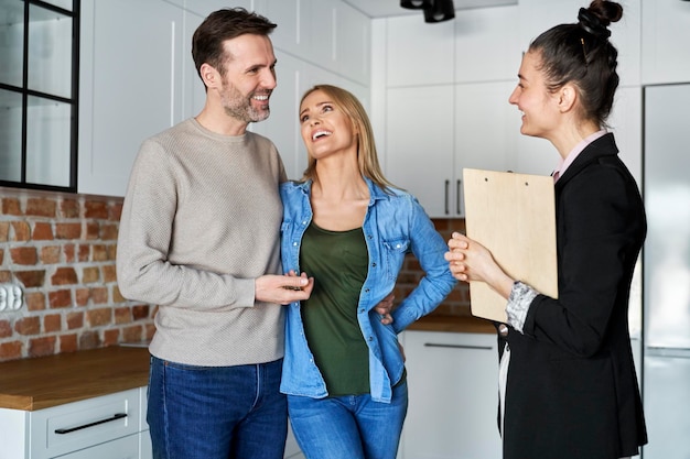 Un couple heureux en train de parler à un agent immobilier.