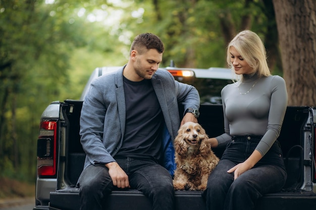 couple heureux en vacances dans la forêt avec un chien près de la voiture