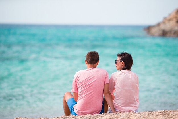 Couple Heureux De Vacances Reposant Sur Le Sable Blanc Et Une Eau Turquoise Immaculée Sur La Plage En Grèce.