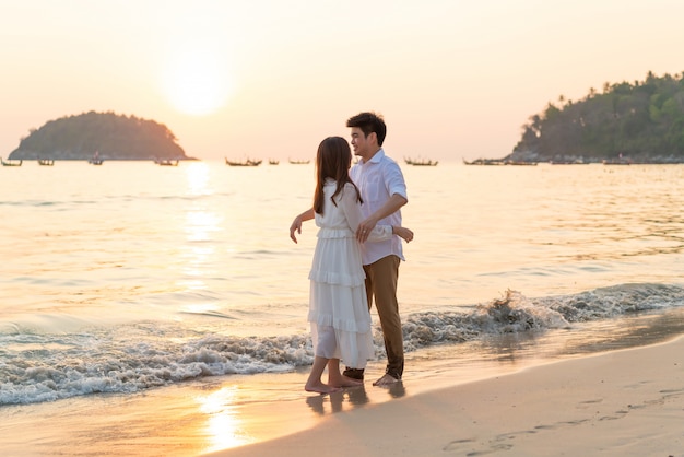 Couple heureux en voyage de noces sur la plage de sable tropicale en été