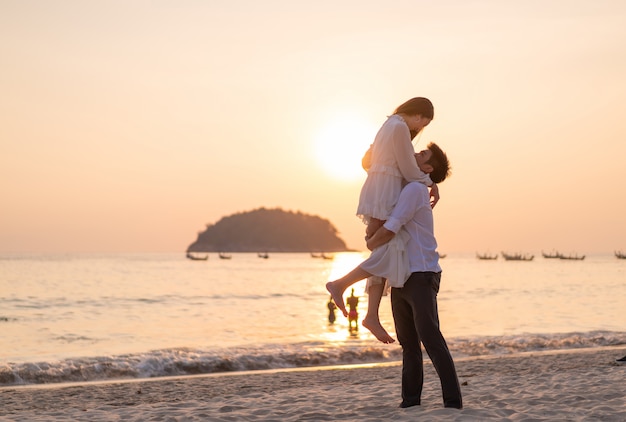 Couple heureux en voyage de noces sur la plage de sable tropicale en été