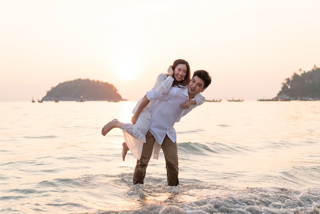 Couple heureux en voyage de noces sur la plage de sable tropicale en été