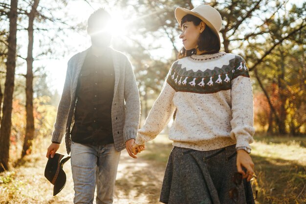 Un couple de hipsters qui se regardent, un couple qui porte de beaux chapeaux et des pulls.