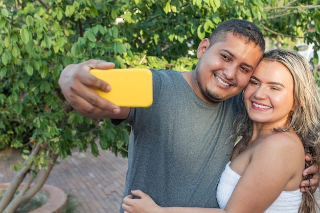 Couple hispanique marchant à l'extérieur dans la rue de la ville, à l'aide d'un téléphone portable