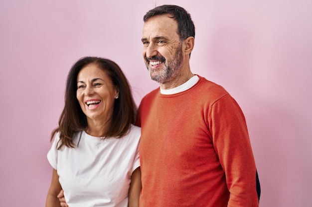 Couple d'homme et de femme d'âge moyen se serrant les coudes debout sur fond rose