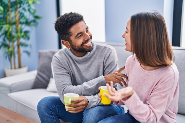 Couple homme et femme assis sur un canapé, boire du café à la maison