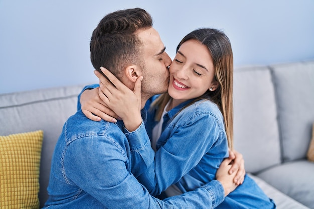 Couple homme et femme assis sur un canapé s'embrassant et s'embrassant à la maison