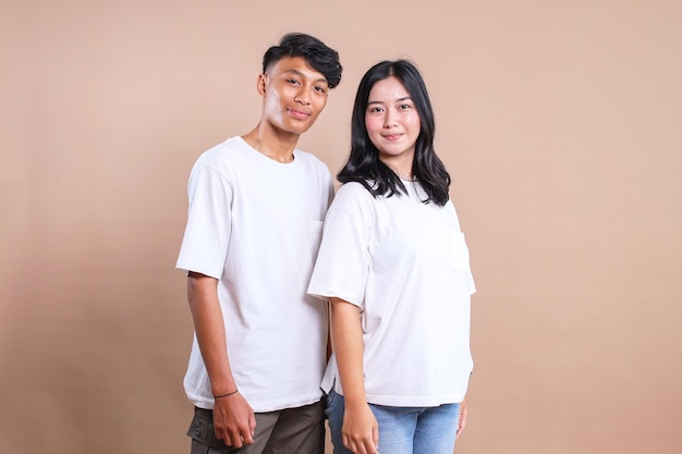 Un couple d'hommes et de femmes asiatiques portant un t-shirt blanc pour une maquette sur fond beige