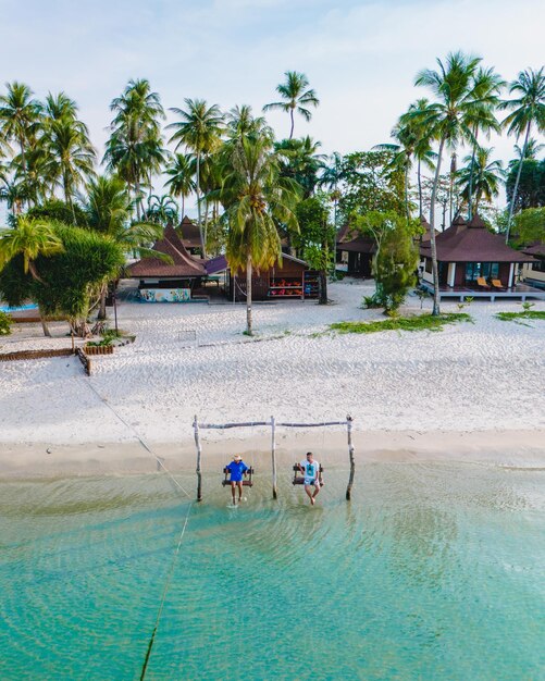 un couple d'hommes et de femmes sur une balançoire à la plage de Koh Muk en Thaïlande