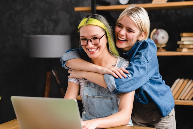 Photo couple homosexuel amies lgbtq lesbiennes sœurs collègues de travail travaillant ensemble étudiant faisant des projets travail d'équipe collectif tout en s'embrassant câlinant se liant au bureau à domicile