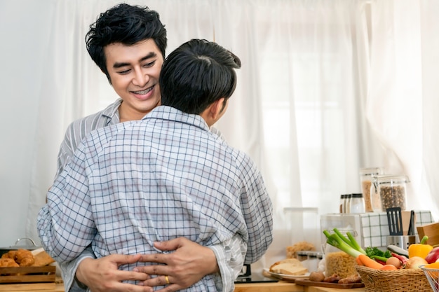 Couple homosexuel asiatique câlin et baiser à la cuisine le matin