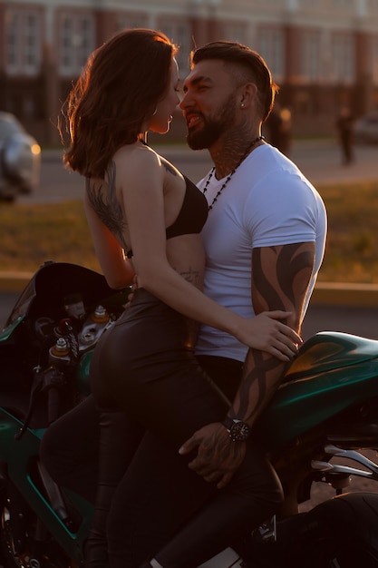 Couple hugging près de moto au coucher du soleil