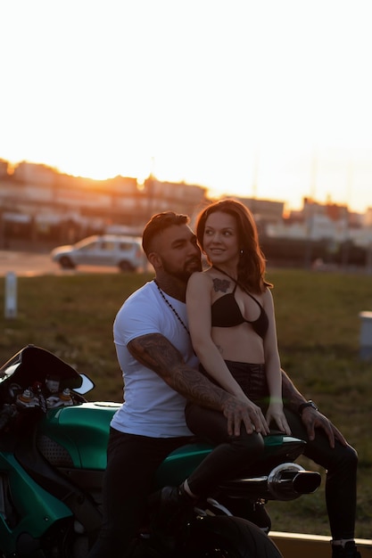 Couple hugging près de moto au coucher du soleil