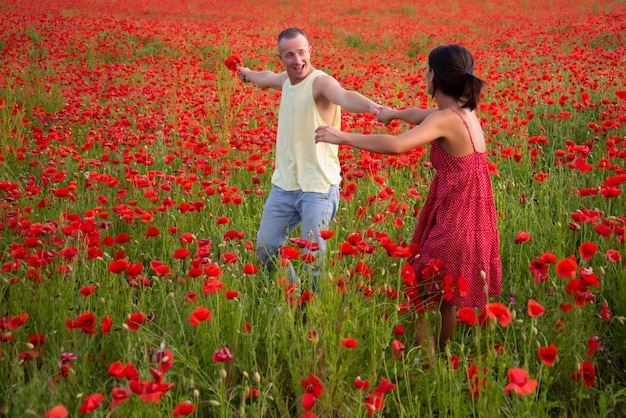 Couple insouciant amoureux sur le champ de printemps de pavot. Bien être danse en famille, nature champêtre. Mode de vie de rêve.