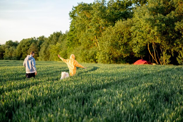 Un couple insouciant marche sur un champ vert au coucher du soleil