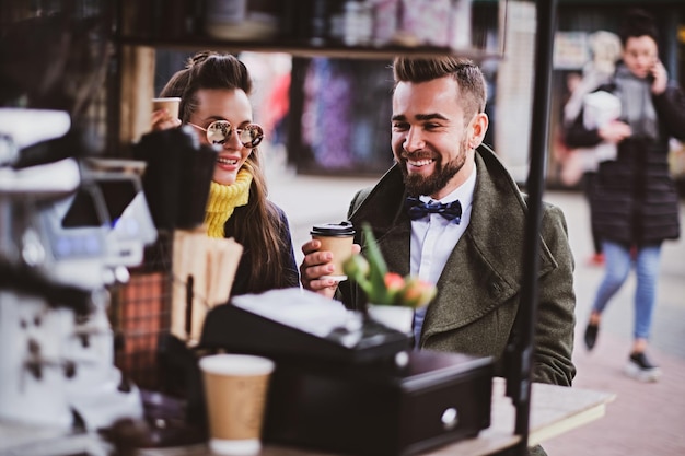 Un couple intelligent et attrayant savoure un café tout en étant assis dehors dans un petit café