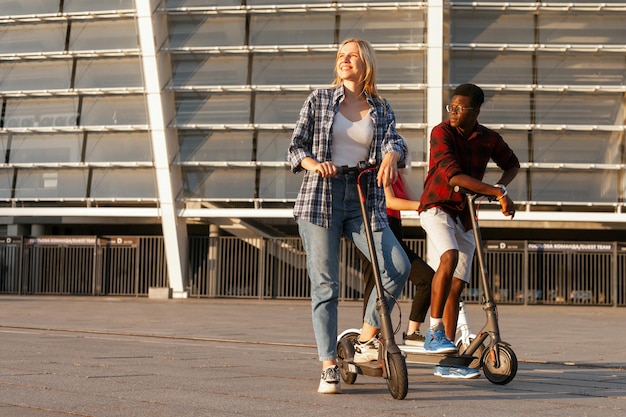 Un couple interracial avec des scooters électriques sourit et regarde le fond