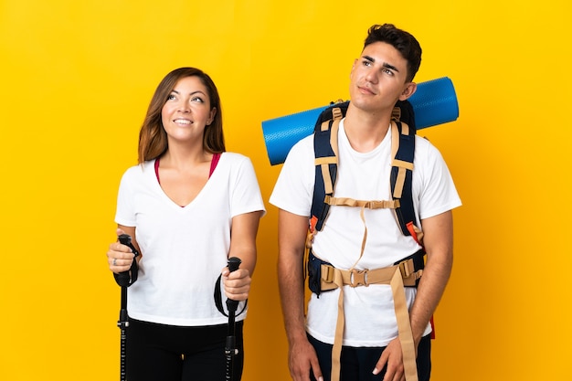 Couple de jeune alpiniste avec un gros sac à dos jaune en pensant à une idée tout en levant les yeux