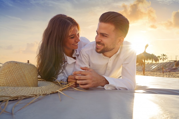 Couple jeune sur le coucher de soleil sur le salon de la plage