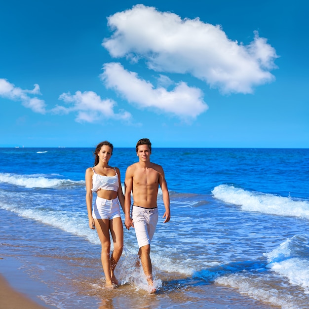 Couple jeune marchant sur le rivage de la plage