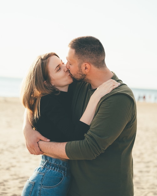 Couple de jeunes adultes debout sur la côte et s'embrasser. Bel homme souriant