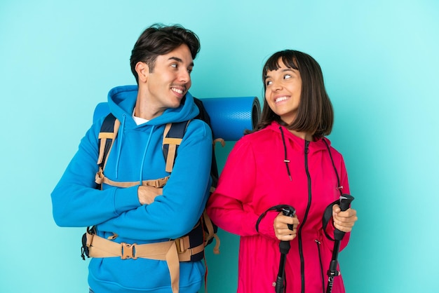 Couple de jeunes alpinistes isolé sur fond bleu regardant par-dessus l'épaule avec un sourire