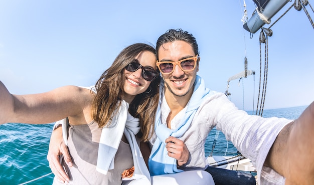 Photo couple de jeunes amoureux prenant selfie en bateau à voile autour du monde