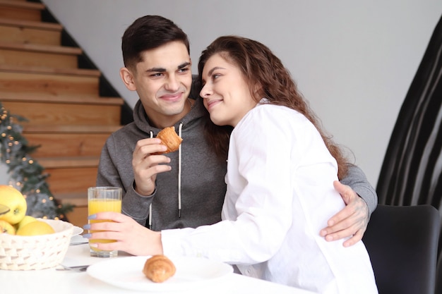 Un couple de jeunes amoureux s'embrassent au petit déjeuner