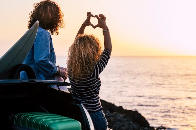Couple de jeunes filles actives amis profiter du coucher de soleil d'été en regardant l'horizon de l'océan ensemble