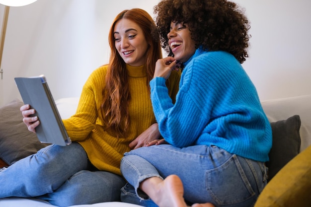 Couple de jeunes filles parlant avec leurs amis via la tablette et restant en contact depuis la maison