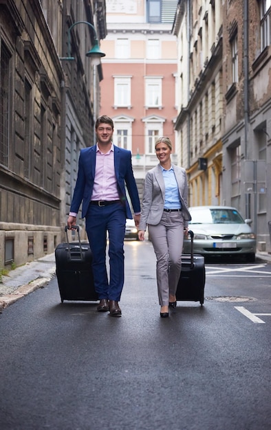 Couple de jeunes gens d'affaires entrant dans l'hôtel de la ville, à la recherche d'une chambre, tenant des valises en marchant dans la rue