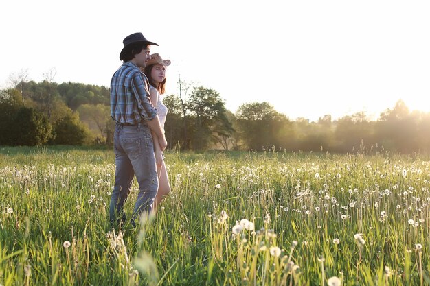 Couple de jeunes gens marchant dans la soirée de printemps au coucher du soleil dans le champ