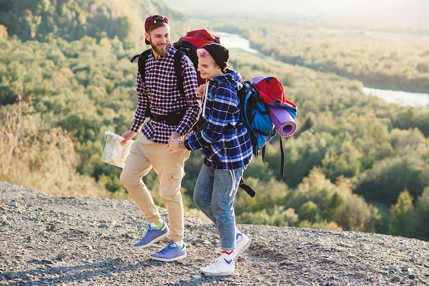 Couple de jeunes hipster avec des sacs à dos de randonnée dans les montagnes pendant un long voyage.