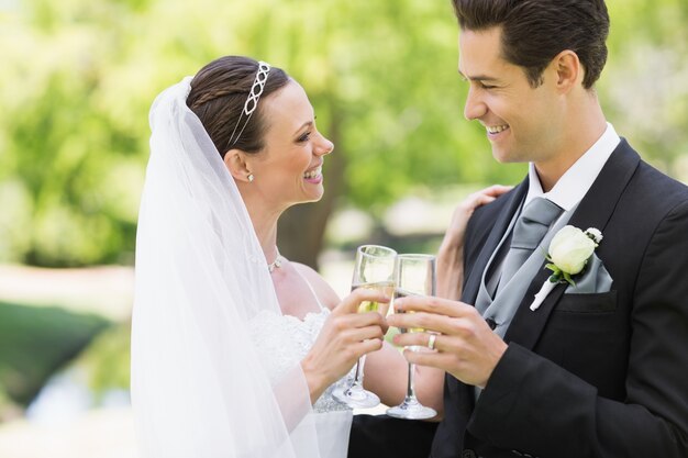 Couple de jeunes mariés grillage champagne dans le parc