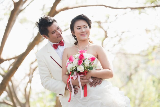 Photo un couple de jeunes mariés tenant un bouquet de fleurs à l'extérieur