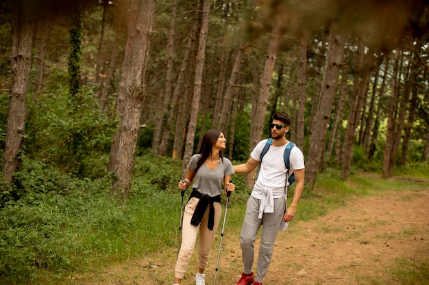 Un couple de jeunes randonneurs avec des sacs à dos se promène dans la forêt