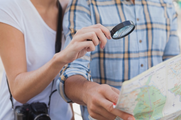 Couple de jeunes touristes à l&#39;aide de la loupe sur la carte