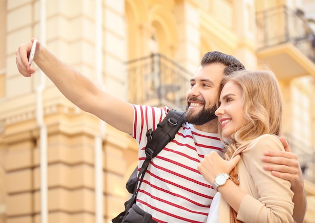 Couple de jeunes touristes prenant selfie dans la rue