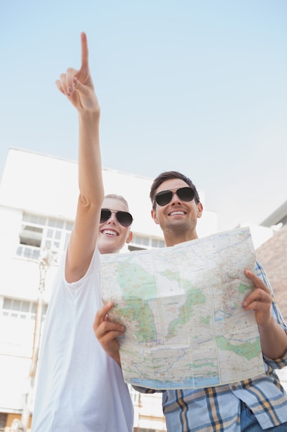 Couple de jeunes touristes en regardant la carte et pointant