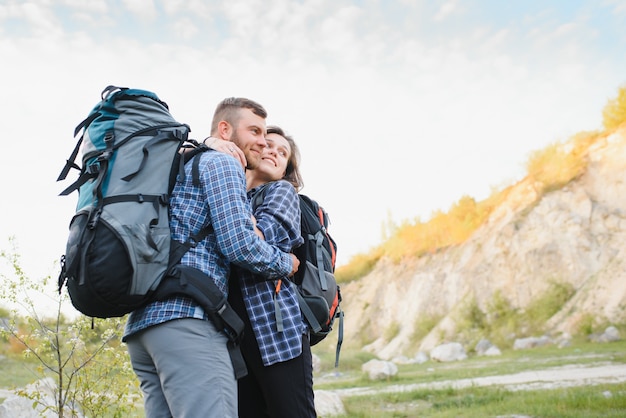 Couple de jeunes voyageurs heureux en randonnée avec des sacs à dos sur le magnifique sentier rocheux