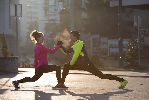 couple de jogging s'échauffant et s'étirant avant de courir le matin dans la ville