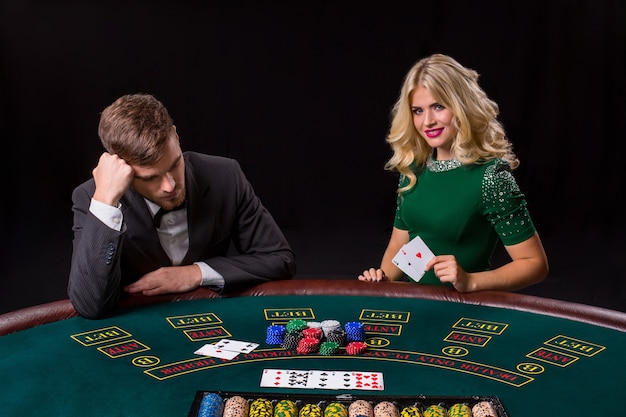 Couple jouant au poker à la table verte. La fille blonde et un gars en costume. bonne victoire, deux as